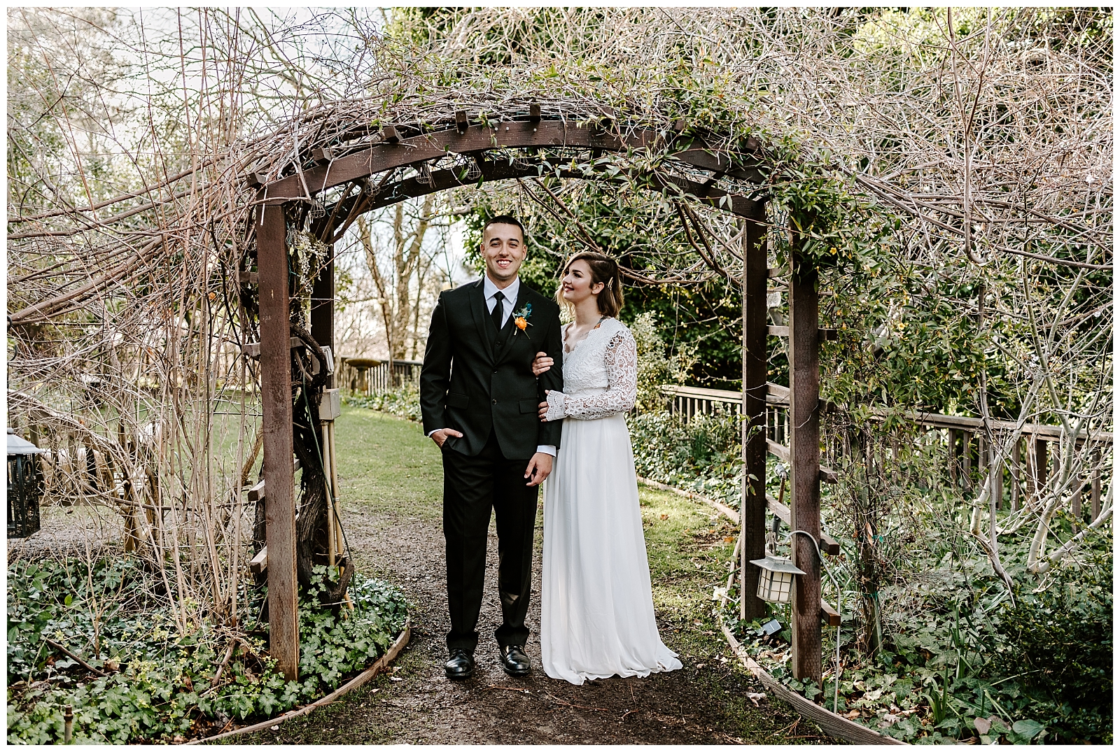 bride and groom standing under a pergola in the garden