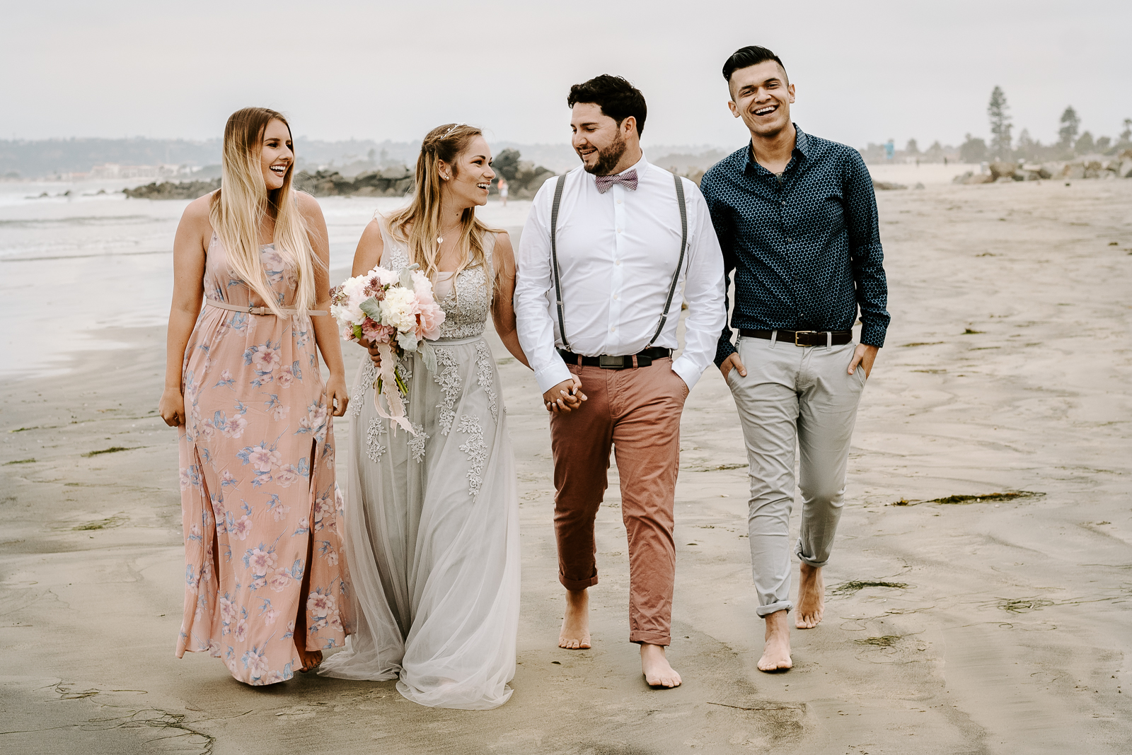 bride and groom walk along with the beach with family on their elopement day.